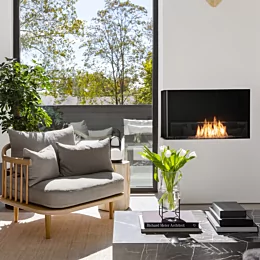 EcoSmart Fire Flex 32LC corner ethanol fireplace warms Long Branch Passive House living room with sleek built-in black feature.